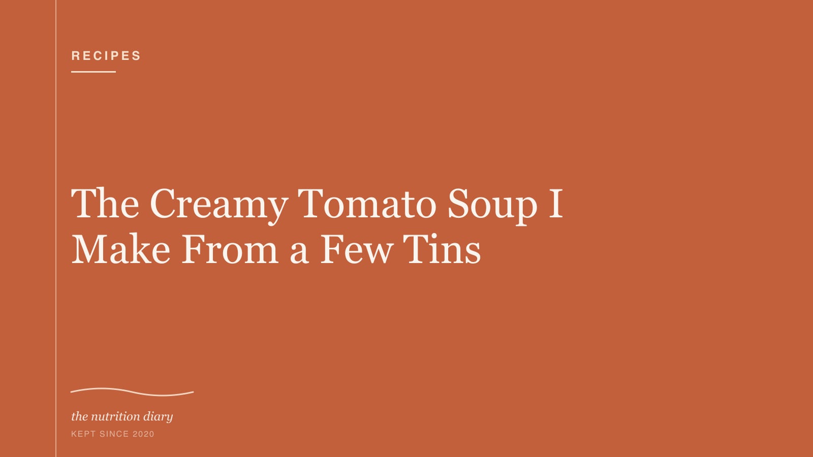 A bowl of deep red tomato soup with a swirl of cream and torn basil leaves on top